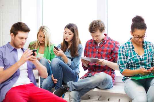 5 adults all looking down at their phones and tablets