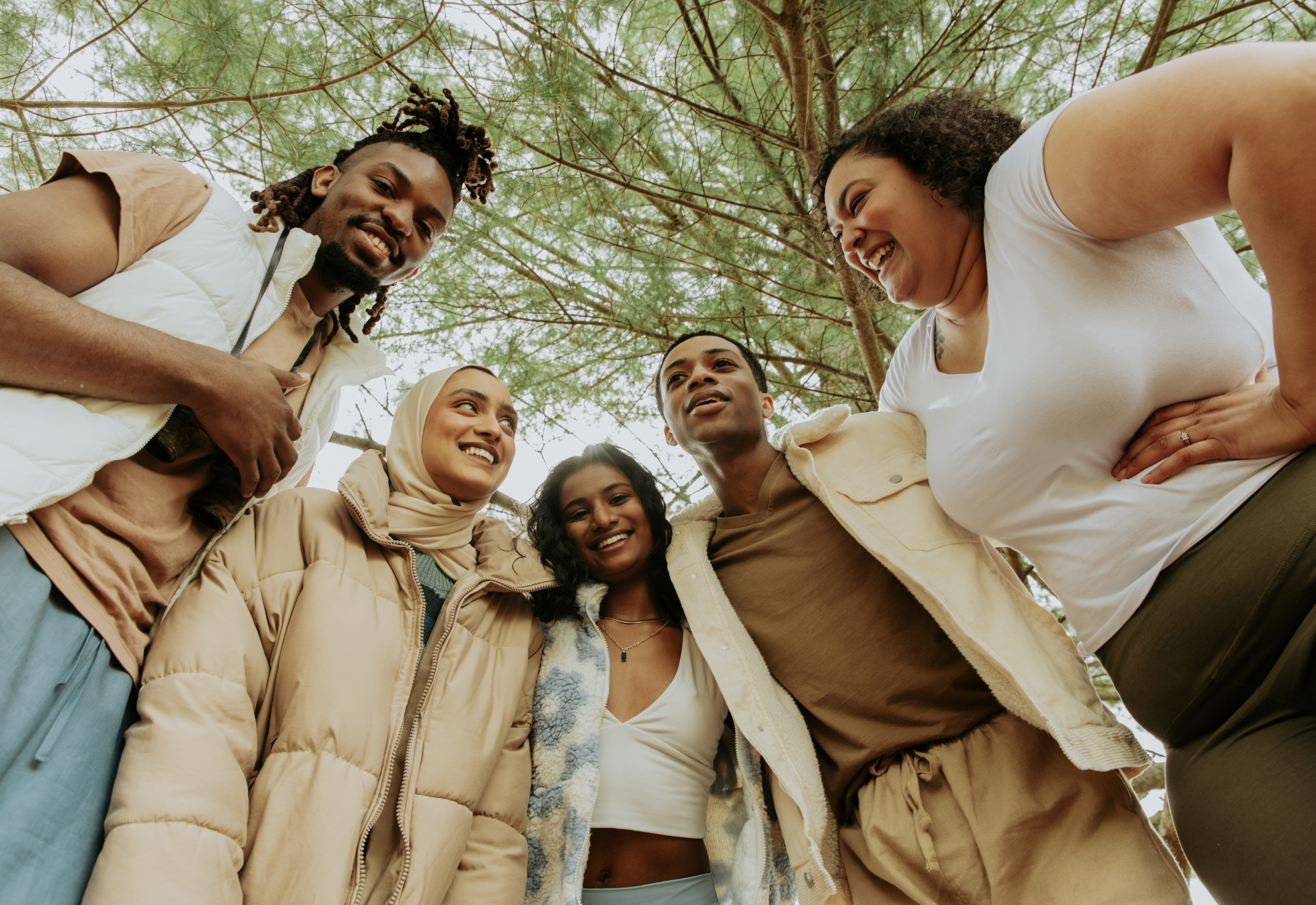 A diverse group of people in a circle beneath trees, representing inclusive research practices.