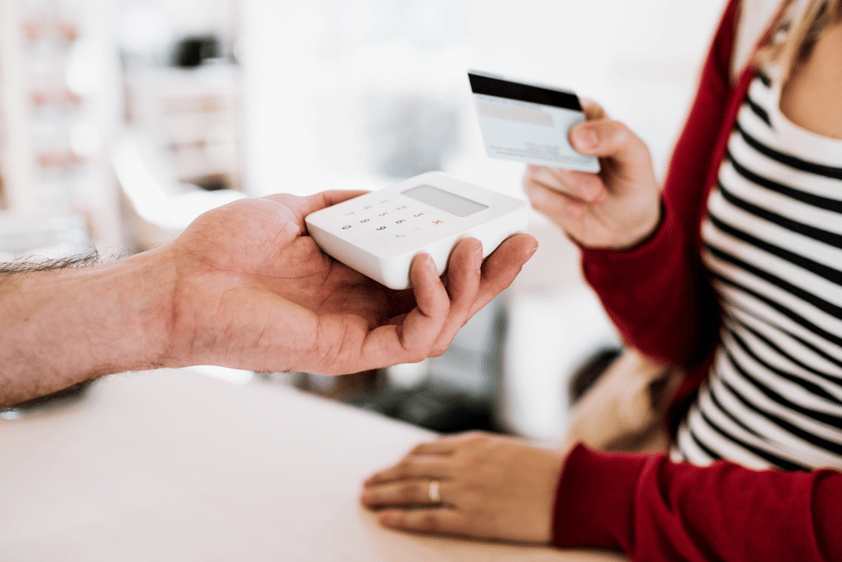 Customer and Shop Assistant Making Contactless Payment Using Credit Card in a Shop as part of retail industry market research