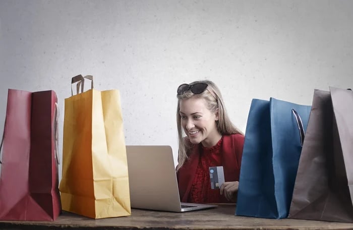 A woman shopping online, surrounded by bags, as part of Retail Industry Market Research