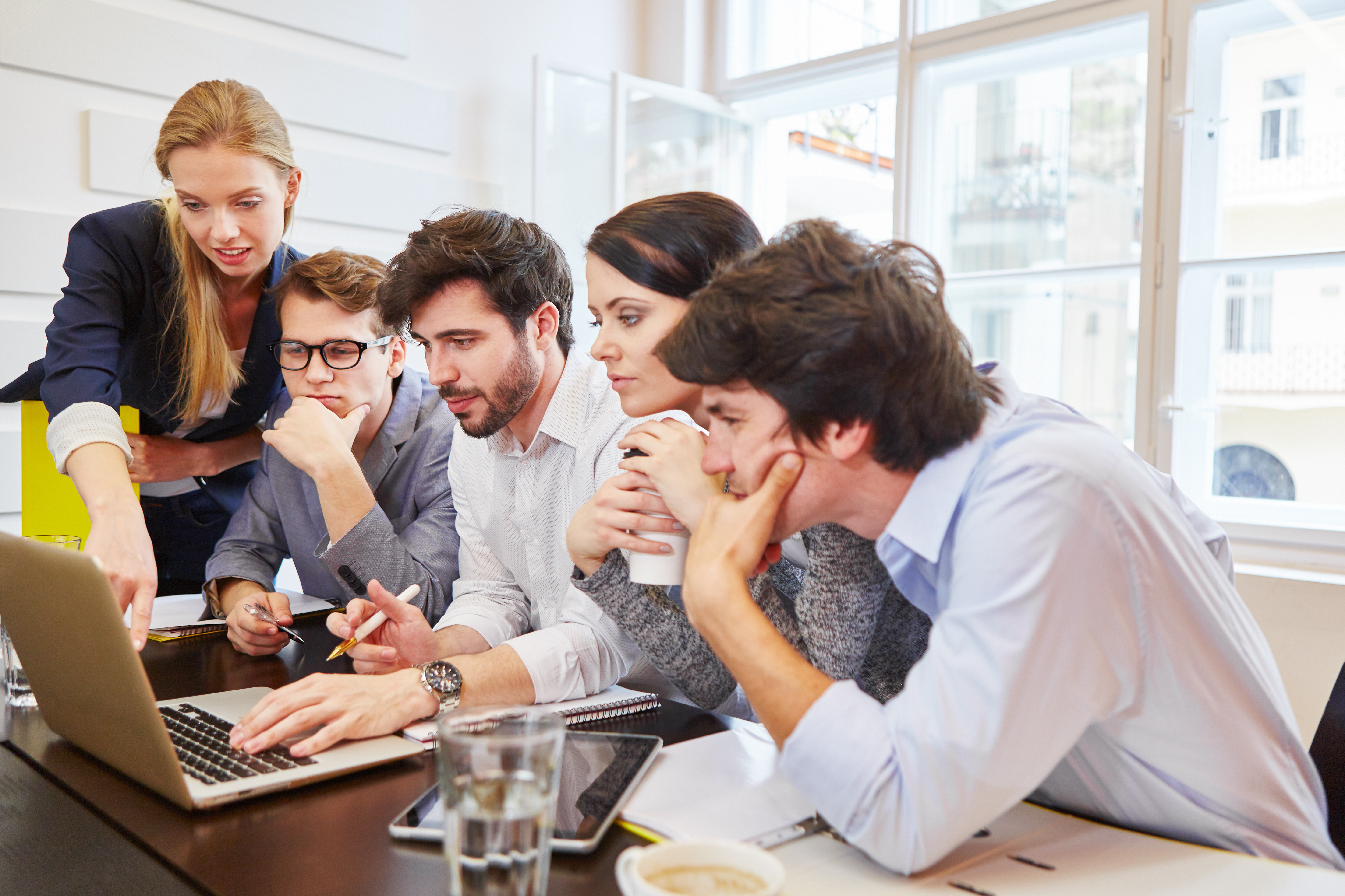 Team of market researchers gathered around a laptop analysing their market research data and insights