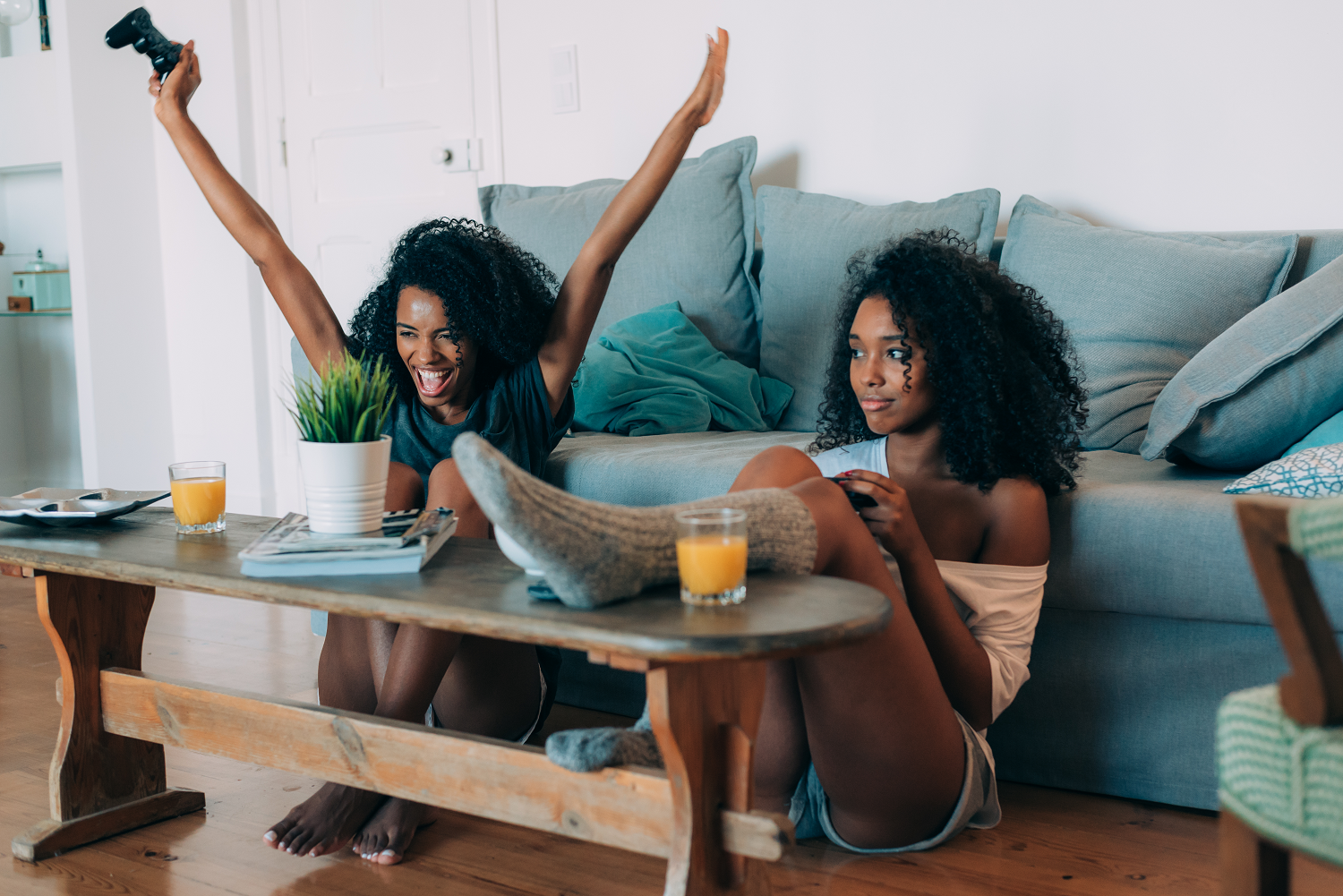 Two young black women sitting in the sofa playing video games as part of an ethnography into video games and gender