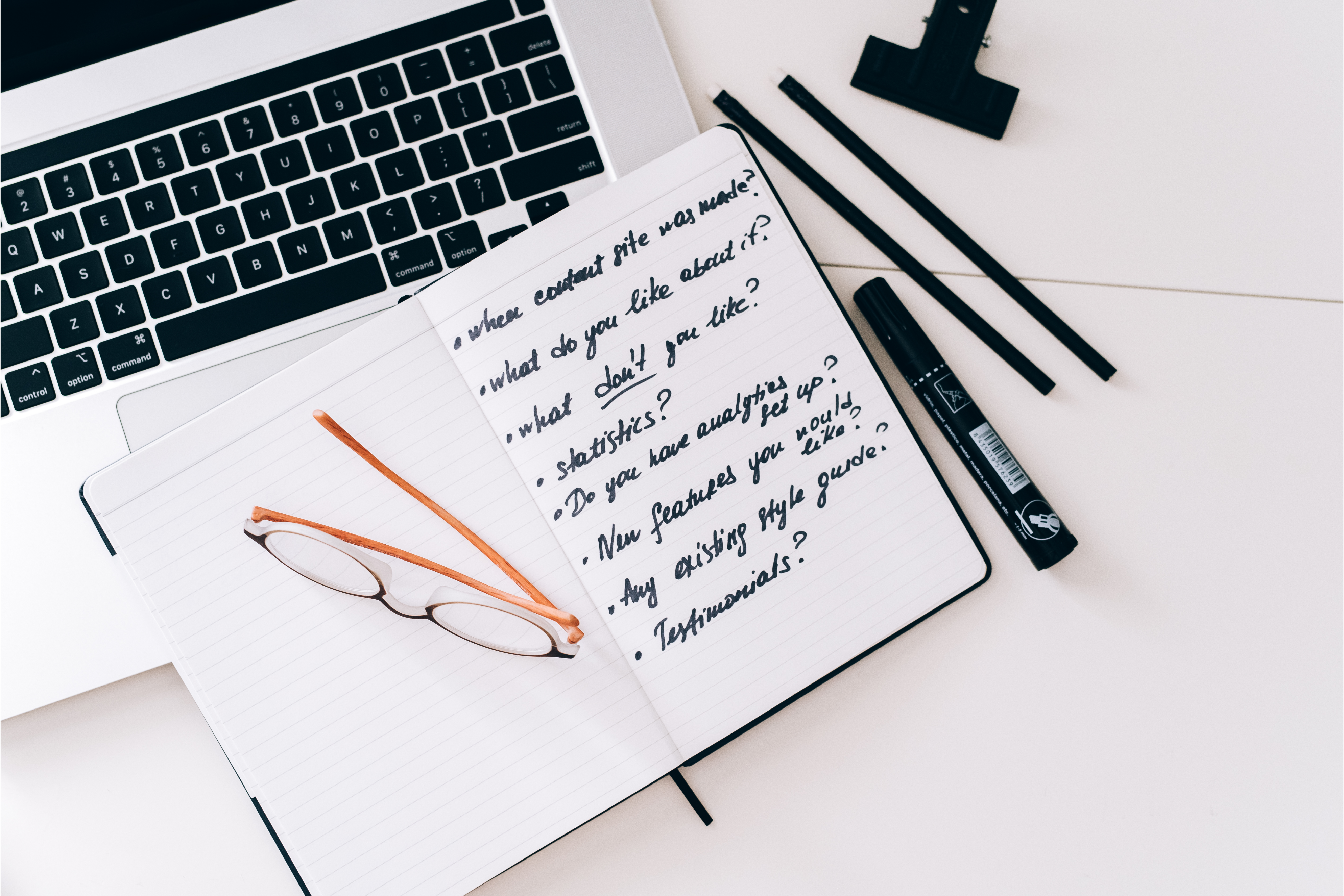 User research screener questions written out on a notebook over a laptop, as advised by a user research recruitment agency