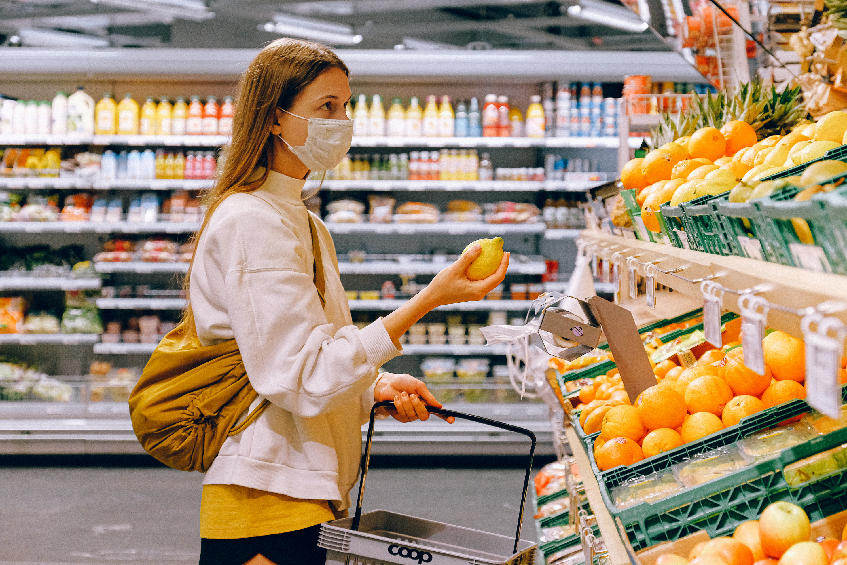 Woman in Yellow Tshirt and Beige jacket Holding a Fruit Stand as part of retail industry market research