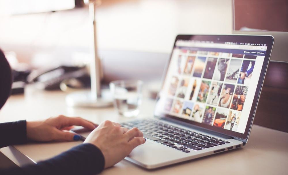 Hands on an open laptop displaying social media photos