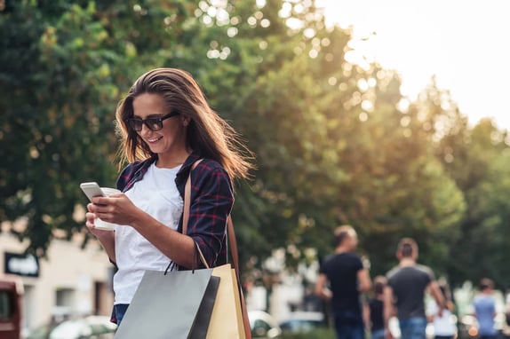 women waling whilst looking at her phone
