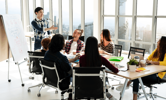 Group of market researchers around a conference room table discussing why to do a design sprint