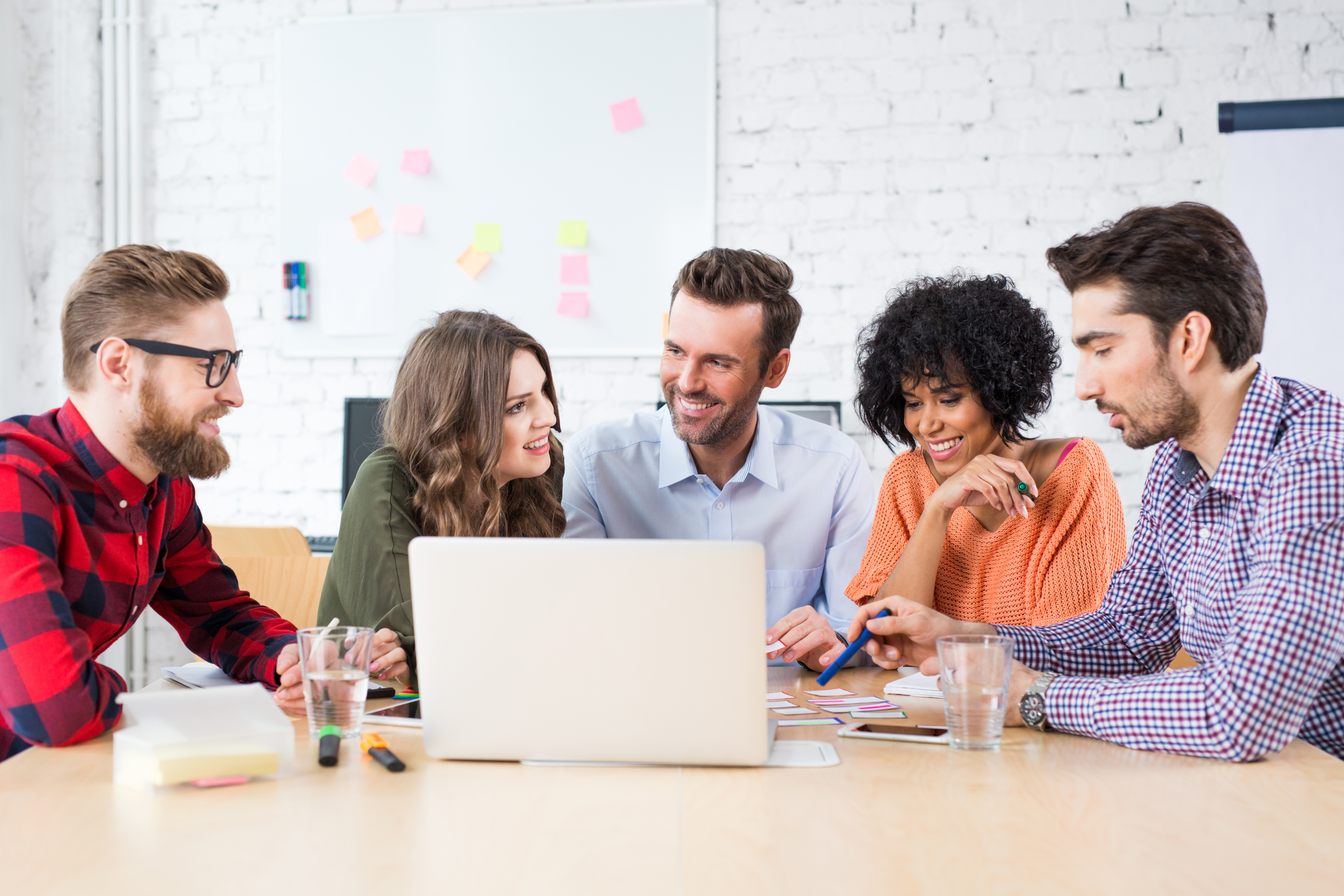 Group of market researchers around a laptop discussing why to do a design sprint