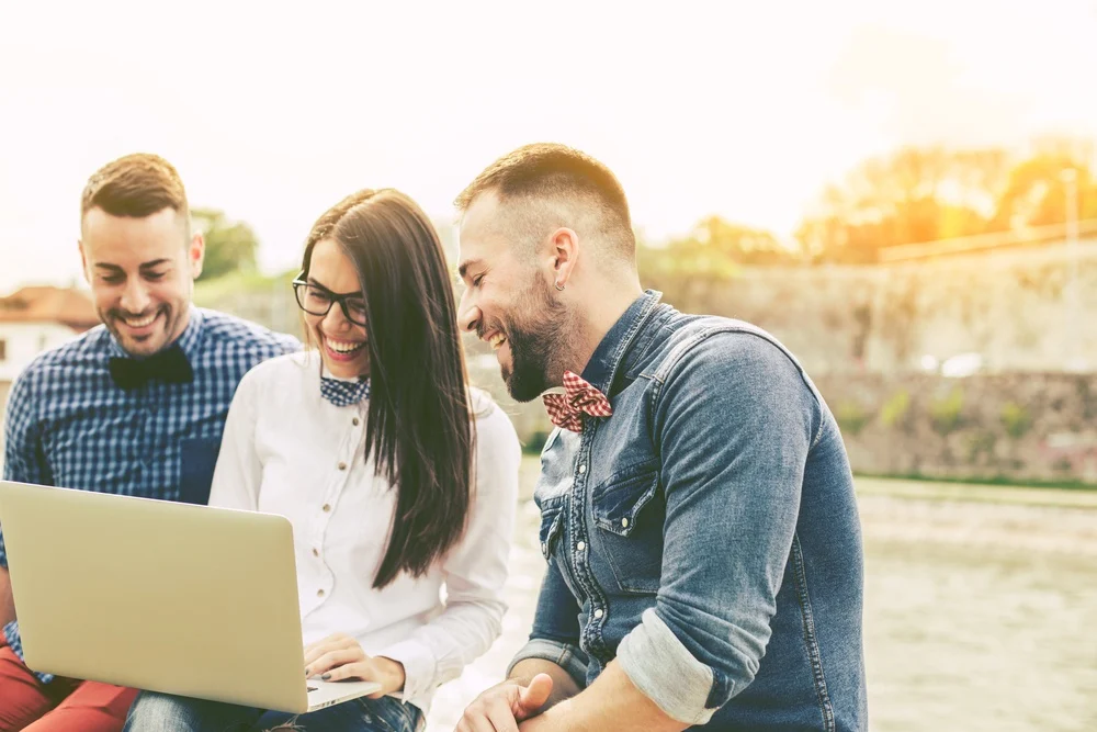 3 people laughing at laptop