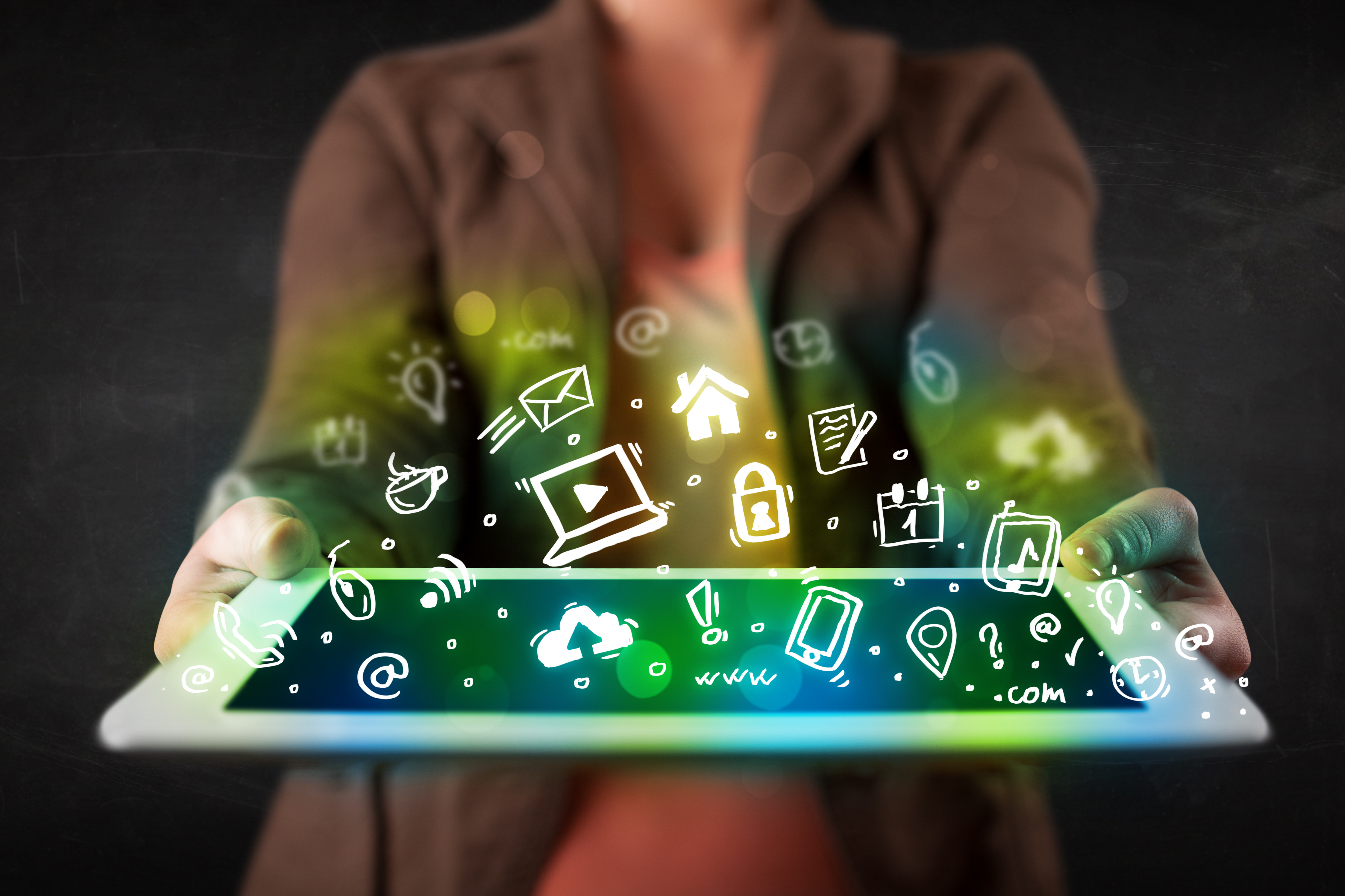 Person holding tablet with green media icons and symbols, representing market research in the media industry.