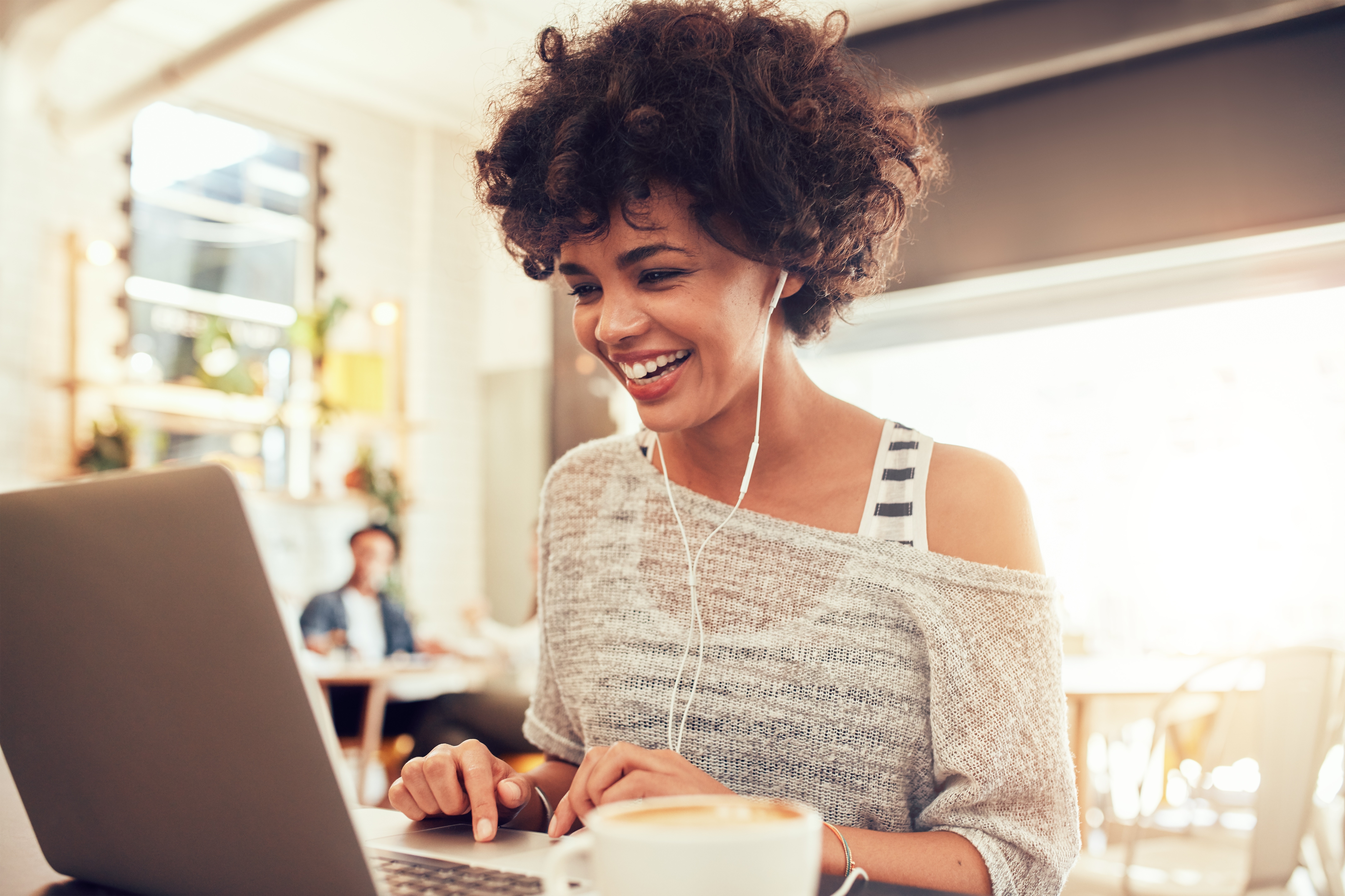 Person on laptop smiling with headphones in to represent moderated user research