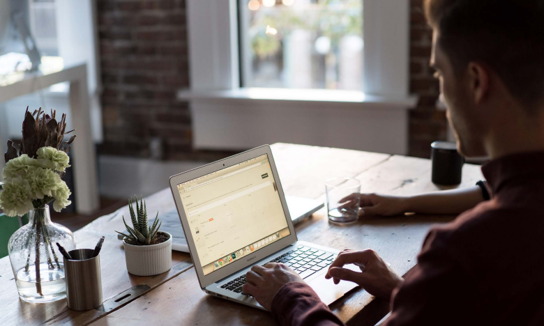 Person on laptop sat at a desk as part of market research online community ideas